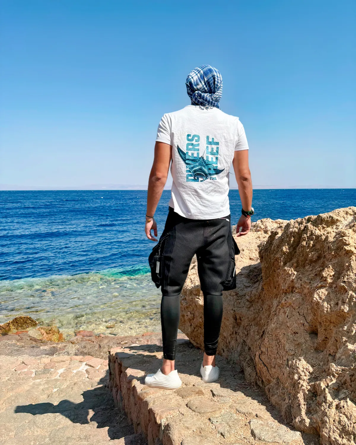 Mo on the rocks in a Divers Reef shirt, looking out at the Red Sea
