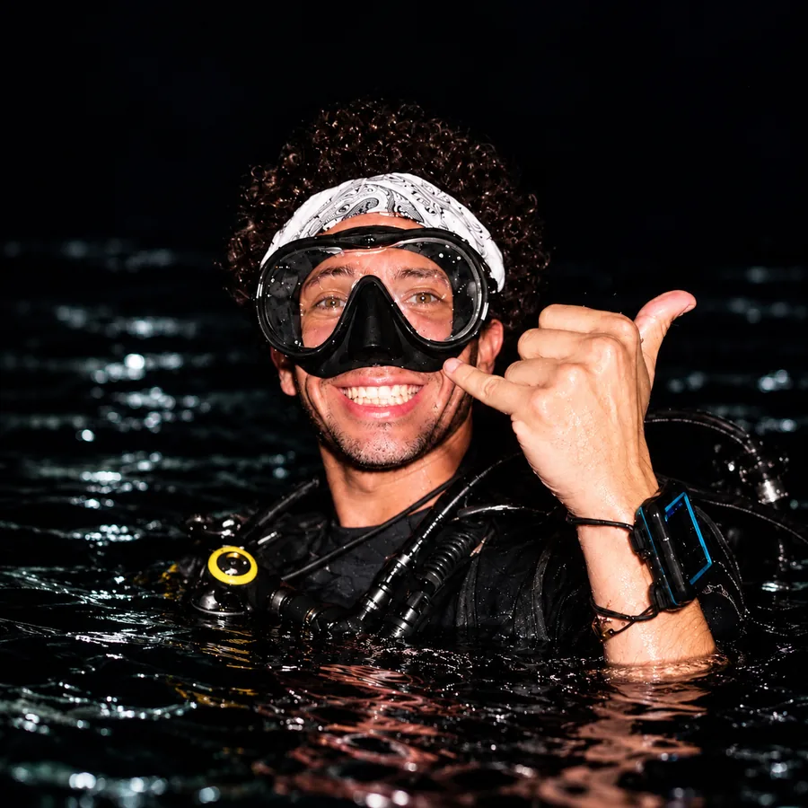 Mo at the surface at night, smiling and giving a shaka